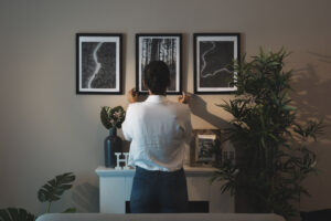 Mujer arreglando cuadros en su casa nueva: aprende cómo decorar tus paredes con estilo