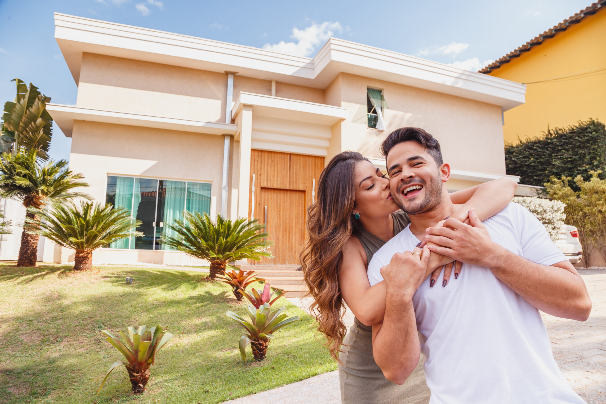 couple in front of new large modern house, outdoors happy for ac