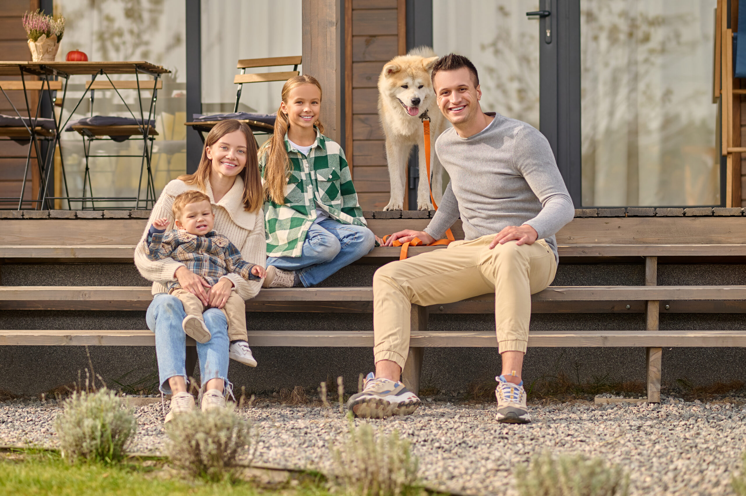 Family sitting on steps looking at camera and dog