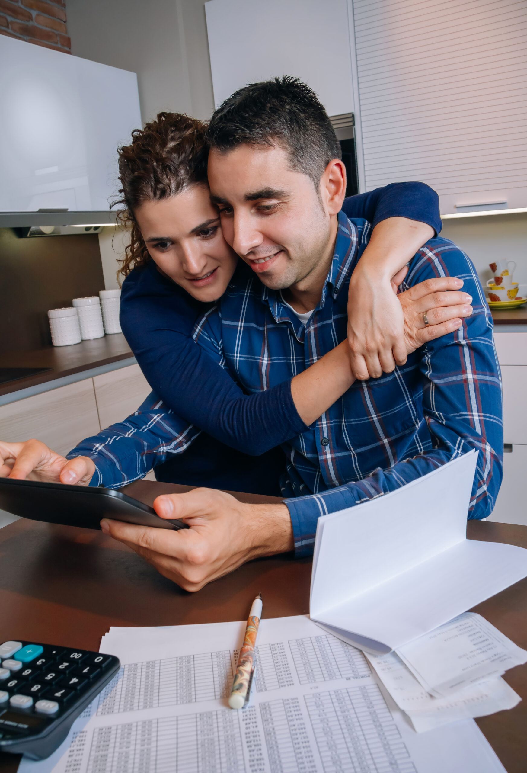 Cheerful couple using digital tablet at kitchen home
