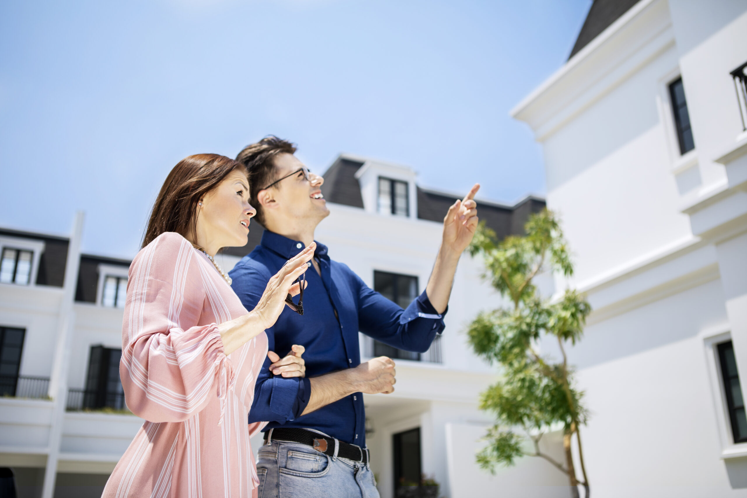 Mature Caucasian couple pointing at the new house