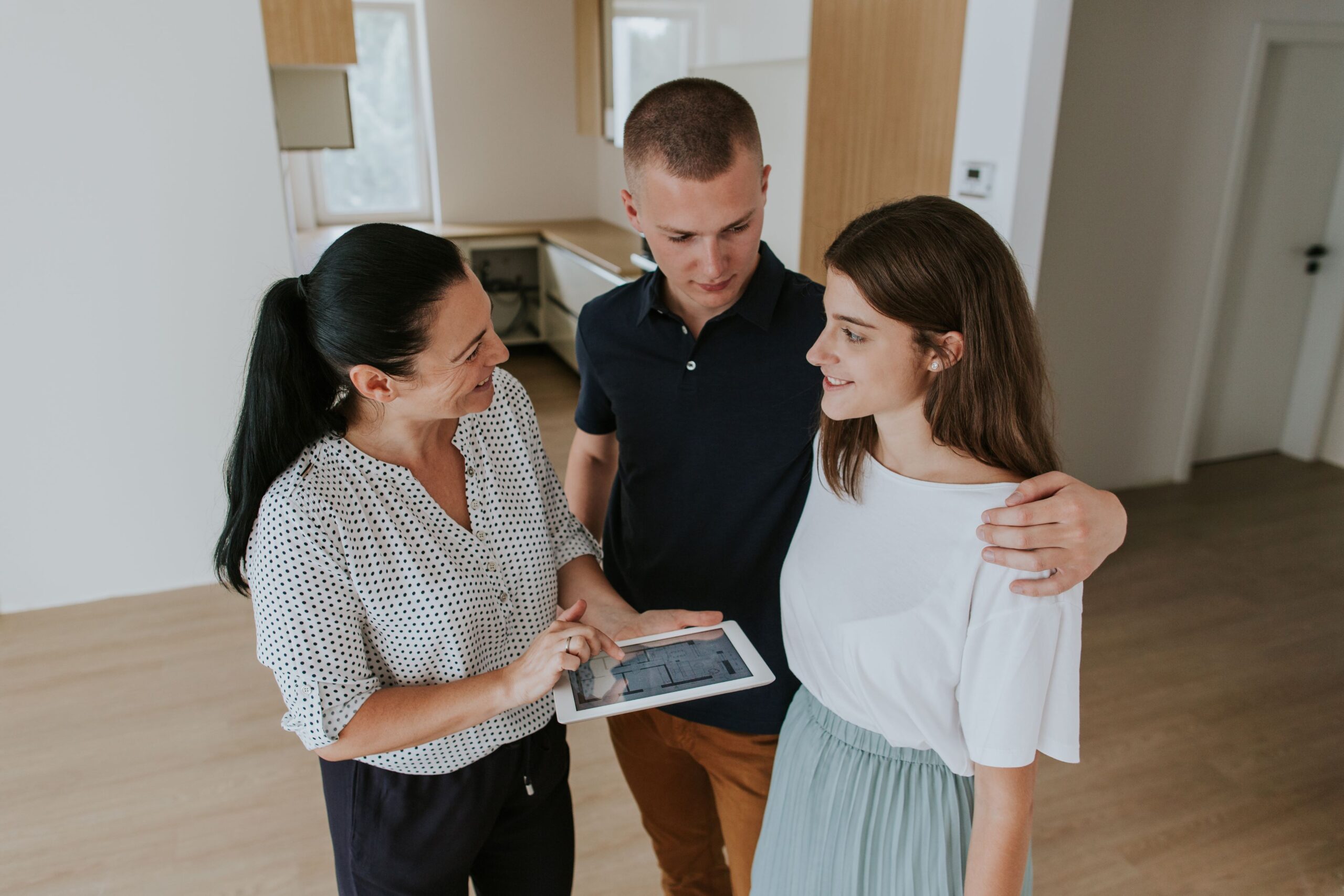 woman-with-digital-tablet-talking-with-couple-standing-floor-home