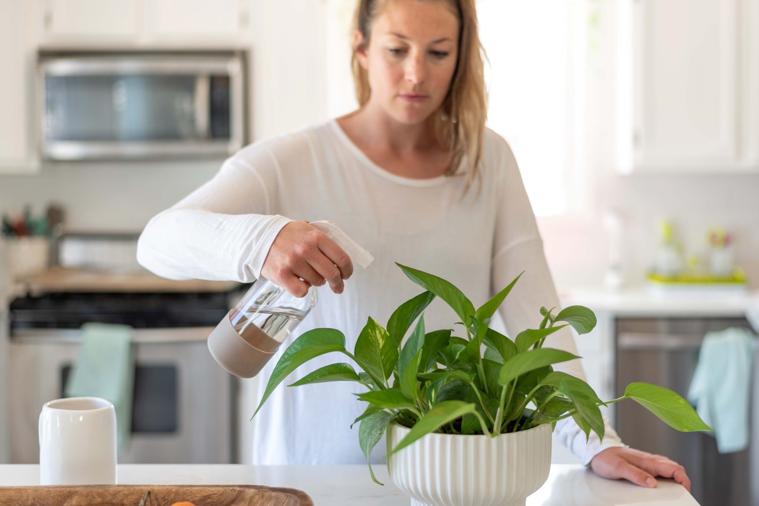 woman-spraying-water-plants-home