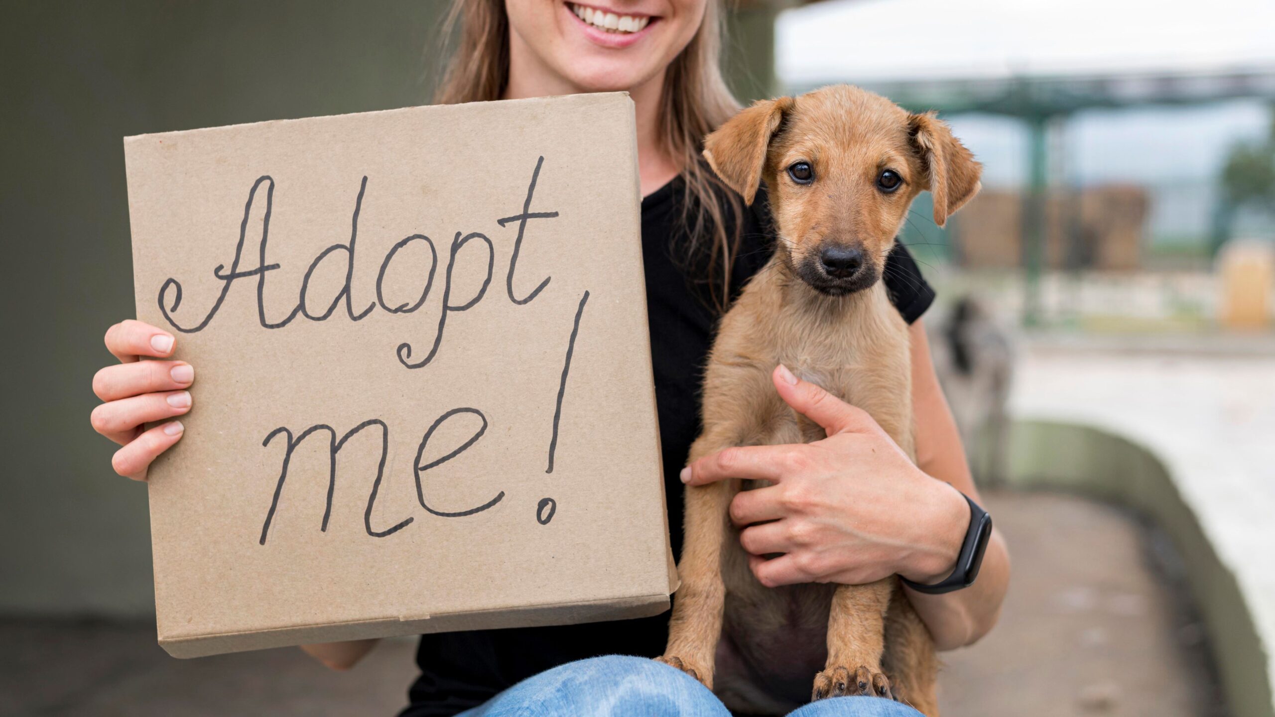 Mujer sonriendo con letrero en mano que dice Adopta una mascota