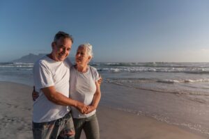 Pareja de la tercera edad paseando por la playa disfrutando de la brisa marina