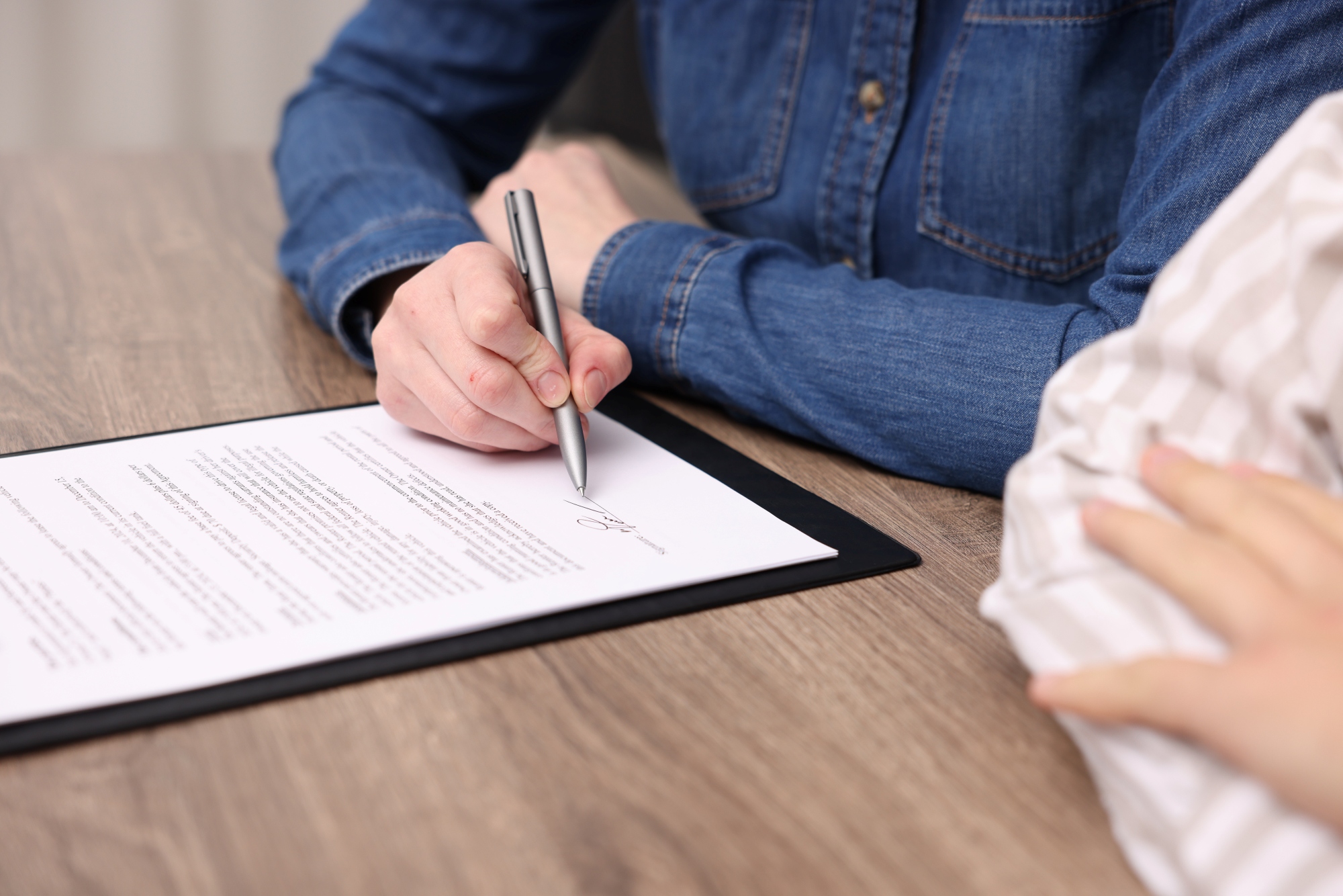 mujer-firmando-un-documento-en-un-primer-plano-frente-a-un-notario