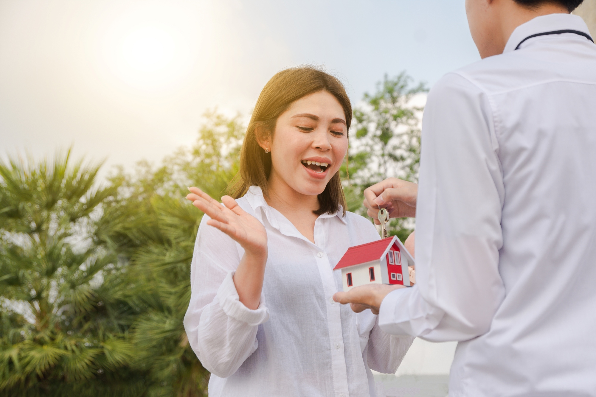 Joven mujer recibiendo llave y casa simbolica de su nuevo hogar